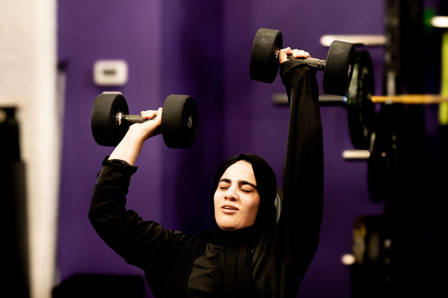 A member pressing dumbbells overhead